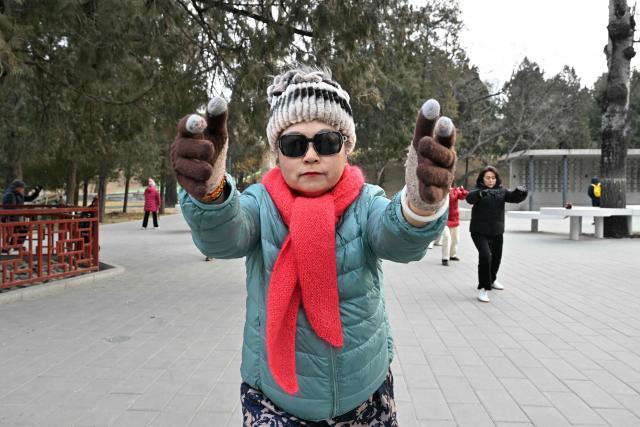 Taichi practitioners move during a session at a park in Beijing on January 17, 2026. (Photo by ADEK BERRY / AFP)