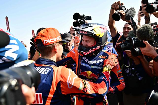 Argentine rider Luciano Benavides (L) with a Ktm 450 Rally Factory is being greeted by Australian rider Daniel Sanders after winning the 48th edition of the Dakar Rally 2026 in Yanbu, Saudi Arabia, on January 17, 2026. (Photo by Giuseppe CACACE / AFP)
