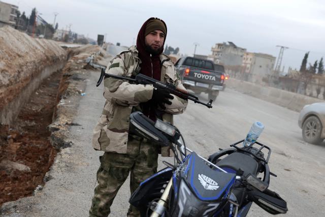 A Syrian army soldier stands guard along the road in Deir Hafer town on January 17, 2026. Syria's army said it took control of the town of Deir Hafer outside Aleppo city on January 17, a day after Kurdish forces agreed to withdraw from the area following recent clashes. In a statement to state television, the army said it had established "full military control" of Deir Hafer, while an AFP correspondent on the ground saw troops deploying inside the town. (Photo by Bakr ALkasem / AFP)