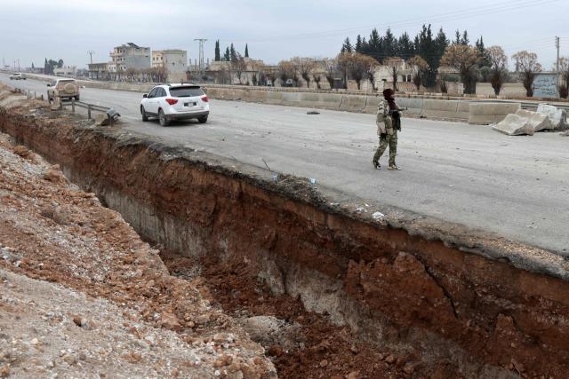 A Syrian army soldier stands guard along the road in Deir Hafer town on January 17, 2026. Syria's army said it took control of the town of Deir Hafer outside Aleppo city on January 17, a day after Kurdish forces agreed to withdraw from the area following recent clashes. In a statement to state television, the army said it had established "full military control" of Deir Hafer, while an AFP correspondent on the ground saw troops deploying inside the town. (Photo by Bakr ALkasem / AFP)