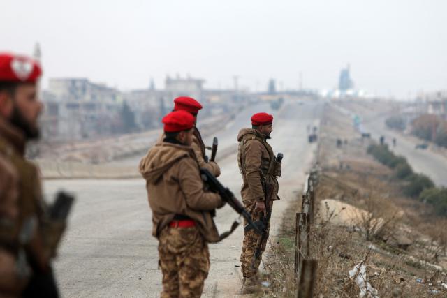 Syrian army soldiers stand guard along the road in Deir Hafer town on January 17, 2026. Syria's army said it took control of the town of Deir Hafer outside Aleppo city on January 17, a day after Kurdish forces agreed to withdraw from the area following recent clashes. In a statement to state television, the army said it had established "full military control" of Deir Hafer, while an AFP correspondent on the ground saw troops deploying inside the town. (Photo by Bakr ALkasem / AFP)
