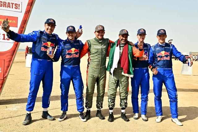 (L-R) Second placed Ford Racing’s Spanish driver Nani Roma and Spanish co?pilot Alex Haro, first placed Dacia Sandriders' Qatari driver Nasser al-Attiyah and Belgian copilot Fabian Lurquin and third placed Ford Racing’s Swedish driver Mattias Ekstrom and Swedish co-pilot Emil Bergkvist pose at the end of the 48th edition of the Dakar Rally 2026 in Yanbu, Saudi Arabia, on January 17, 2026. (Photo by Giuseppe CACACE / AFP)