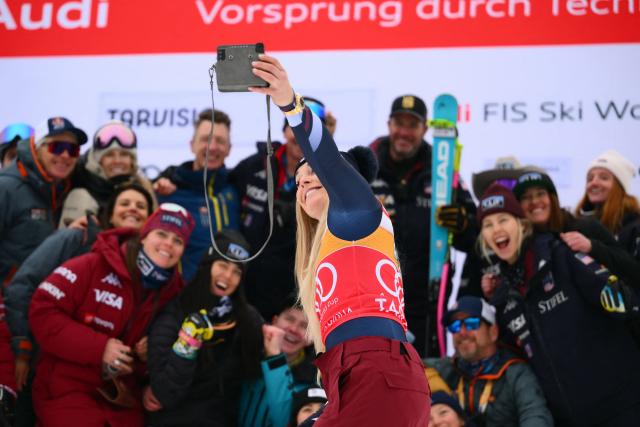 US' Lindsey Vonn, third, snaps a selfie with her team during the podium ceremony of the Women's Downhill event of FIS Alpine Skiing World Cup in Tarvisio, Italy on January 17, 2026. Italy's Nicol Delago won the race ahead of Germany's Kira Weidle, second, and US' Lindsey Vonn, third. (Photo by Marco BERTORELLO / AFP)