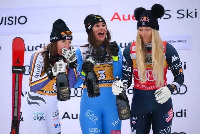 Italy's Nicol Delago (C), winner, Germany's Kira Weidle, second, and US' Lindsey Vonn (R), third, celebrate on the podium of the Women's Downhill event of FIS Alpine Skiing World Cup in Tarvisio, Italy on January 17, 2026. (Photo by Marco BERTORELLO / AFP)