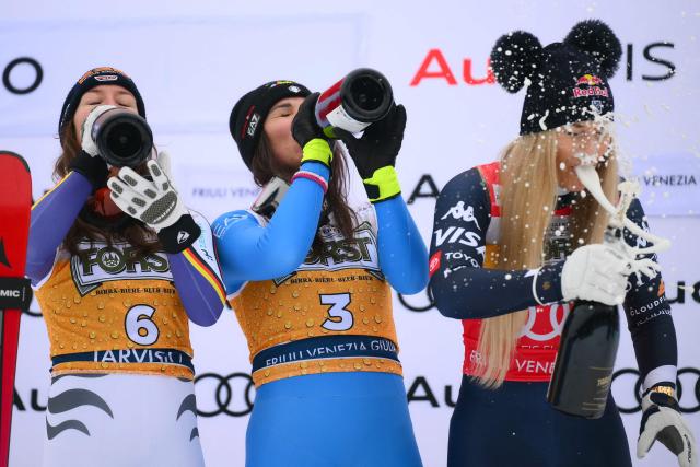 TOPSHOT - Italy's Nicol Delago (C), winner, Germany's Kira Weidle, second, and US' Lindsey Vonn (R), third, celebrate on the podium of the Women's Downhill event of FIS Alpine Skiing World Cup in Tarvisio, Italy on January 17, 2026. (Photo by Marco BERTORELLO / AFP)