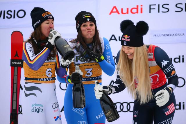 Italy's Nicol Delago (C), winner, Germany's Kira Weidle, second, and US' Lindsey Vonn (R), third, celebrate on the podium of the Women's Downhill event of FIS Alpine Skiing World Cup in Tarvisio, Italy on January 17, 2026. (Photo by Marco BERTORELLO / AFP)