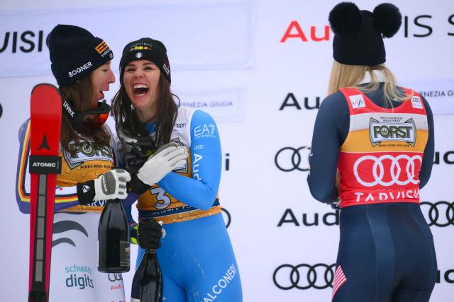 Italy's Nicol Delago (C), winner, Germany's Kira Weidle, second, and US' Lindsey Vonn (R), third, celebrate on the podium of the Women's Downhill event of FIS Alpine Skiing World Cup in Tarvisio, Italy on January 17, 2026. (Photo by Marco BERTORELLO / AFP)