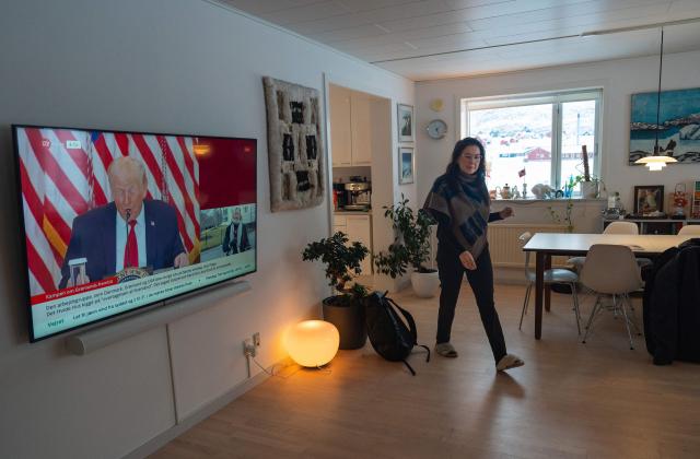 Ulrikke Andersen, a 40-year-old tour operator is pictured at her home with US President Donald Trump is seen on the TV in Nuuk, Greenland on January 16, 2026. Ulrikke Andersen says she will plan to leave Greenland in the case of a war or US invasion as US President Donald Trump's designs to take over the Arctic island who no signs of letting up. (Photo by Alessandro RAMPAZZO / AFP)