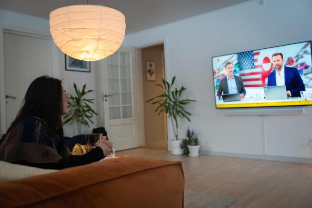 Ulrikke Andersen, a 40-year-old tour operator watches the news on TV at her home in Nuuk, Greenland on January 16, 2026. Ulrikke Andersen says she will plan to leave Greenland in the case of a war or US invasion as US President Donald Trump's designs to take over the Arctic island who no signs of letting up. (Photo by Alessandro RAMPAZZO / AFP)