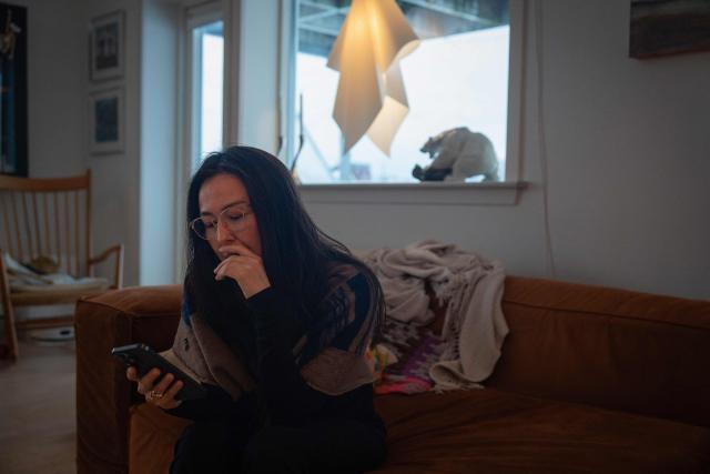 Ulrikke Andersen, a 40-year-old tour operator looks at her phone at her home in Nuuk, Greenland on January 16, 2026. Ulrikke Andersen says she will plan to leave Greenland in the case of a war or US invasion as US President Donald Trump's designs to take over the Arctic island who no signs of letting up. (Photo by Alessandro RAMPAZZO / AFP)