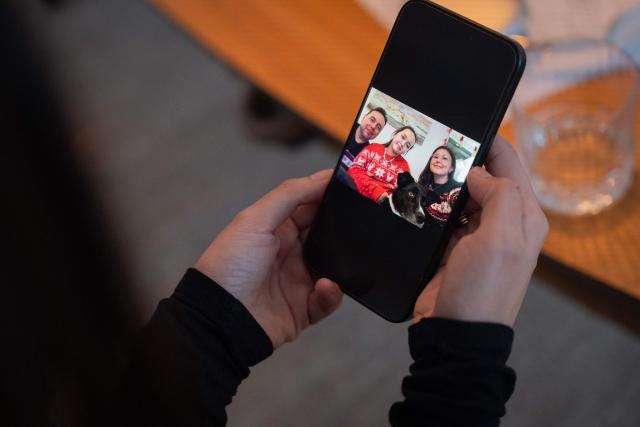 Ulrikke Andersen, a 40-year-old tour operator looks at a recent family picture on her cellphone at her home in Nuuk, Greenland on January 16, 2026. Ulrikke Andersen says she will plan to leave Greenland in the case of a war or US invasion as US President Donald Trump's designs to take over the Arctic island who no signs of letting up. (Photo by Alessandro RAMPAZZO / AFP)