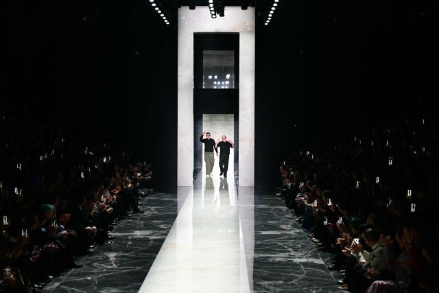 Italian designers Stefano Gabbana and Domenico Dolce (R) greet the audience at the end of the Dolce & Gabbana collection show at Milan's fashion week for the Men's Fall/Winter 2026-2027, on January 17, 2026 in Milan. (Photo by Stefano RELLANDINI / AFP)