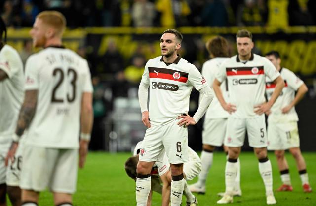 St Pauli's US midfielder #06 James Sands (C) and his teammates stand on the pitch after they were defeated in the German first division Bundesliga football match between BVB Borussia Dortmund and FC St Pauli in Dortmund, western Germany, on January 17, 2026. (Photo by INA FASSBENDER / AFP) / DFL REGULATIONS PROHIBIT ANY USE OF PHOTOGRAPHS AS IMAGE SEQUENCES AND/OR QUASI-VIDEO