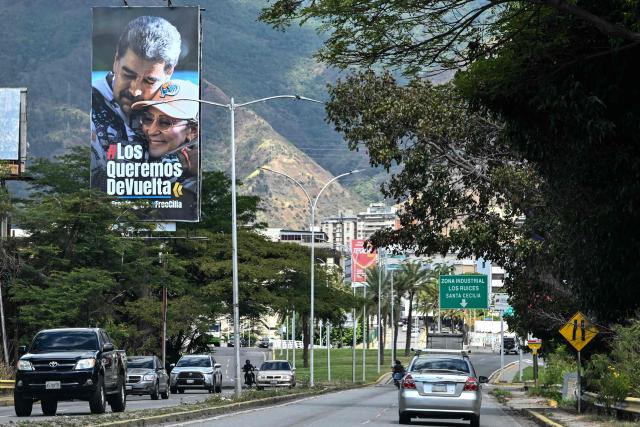 Cars drive along the Francisco Fajardo highway, where a billboard featuring an image of ousted Venezuelan President Nicolas Maduro and his wife Cilia Flores reads “We want you back,” in Caracas on January 17, 2026. (Photo by Ronaldo SCHEMIDT / AFP)