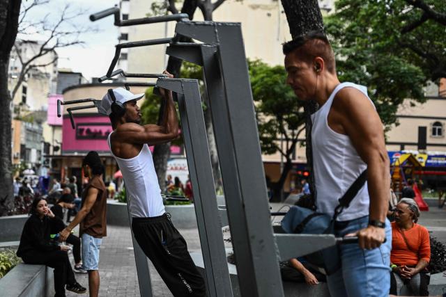 Men exercise at La Candelaria square, an outdoor public gym, in Caracas on January 17, 2026. (Photo by Ronaldo SCHEMIDT / AFP)