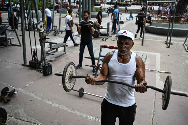 Men exercise at La Candelaria square, an outdoor public gym, in Caracas on January 17, 2026. (Photo by Ronaldo SCHEMIDT / AFP)