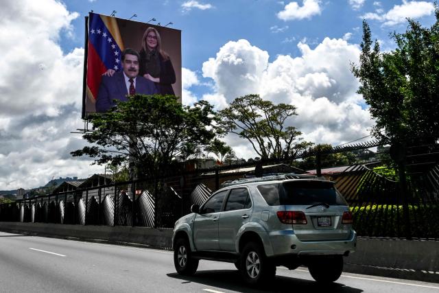 A vehicle drives along the Francisco Fajardo highway, where a billboard displays an image of ousted Venezuelan President Nicolas Maduro and his wife Cilia Flores, in Caracas on January 17, 2026. (Photo by Ronaldo SCHEMIDT / AFP)