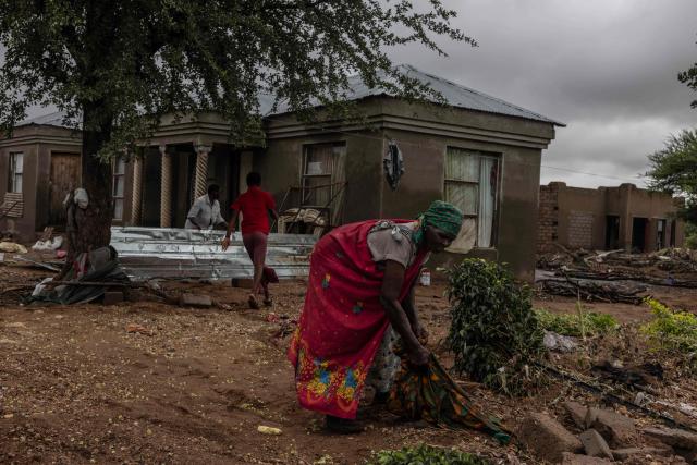 A woman retrieves items from her garden following floods in Mbaula village, 50 km from Giyani on January 17, 2026 following heavy rains over much of the Limpopo Province, South Africa. Heavy rains have drenched the northeast of the country since late last year, claiming at least 30 lives. (Photo by Paul Botes / AFP)