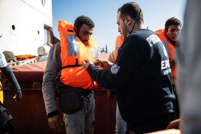 A crew member of the Sider, a merchant ship, helps a migrant suffering from severe dehydration and seasickness to be evacuated by crew members of the "Ocean Viking" rescue ship, in the search-and-rescue zone in international waters off the coast of Libya, on January 17, 2026. Crew members of the Ocean Viking rescue ship evacuated 44 migrants who had been rescued by a merchant ship a few days earlier in Libyas search-and-rescue zone in international waters. They were suffering from severe dehydration, seasickness, and a lack of medical care. Some were unable to walk and had to be evacuated on stretchers. They had left Libya a couple of days earlier aboard a fiberglass boat, hoping to reach the Italian coast before being shipwrecked in rough seas and rescued by a Tanzanian-flagged merchant ship. (Photo by Sameer Al-DOUMY / AFP)