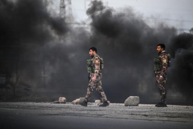 Kurdish forces are seen at the entrance to the city of Tabqa after withdrawing from the towns in the area, in the northern Syrian Raqa province, on January 17, 2026. Syria's army took control of swathes of northern Syria and threatened to bomb parts of Raqa province on January 17, after Kurdish forces pulled back from territory they had held for over a decade. The Syrian army said it had begun entering the city of Tabqa in Raqa province, adding that it was "encircling" the Kurdish forces at their military airport. (Photo by Delil SOULEIMAN / AFP)
