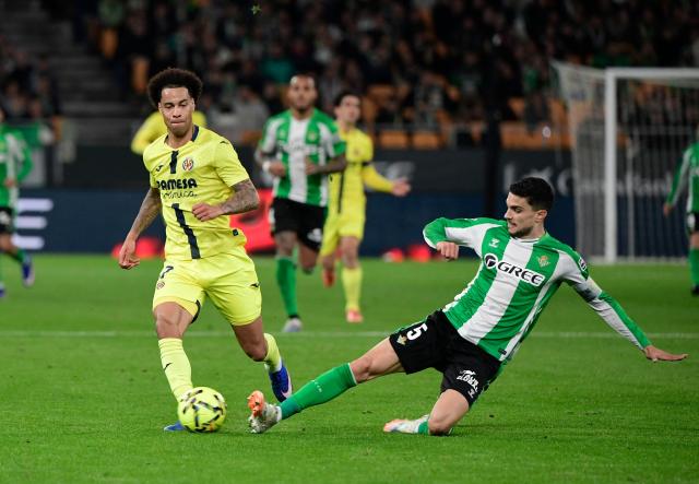 Villarreal's Canadian midfielder #17 Tajon Buchanan (L) fights for the ball with Real Betis' Spanish defender #05 Marc Bartra during the Spanish league football match between Real Betis and Villarreal CF at Benito Villamarin Stadium in Seville on January 17, 2026. (Photo by CRISTINA QUICLER / AFP)