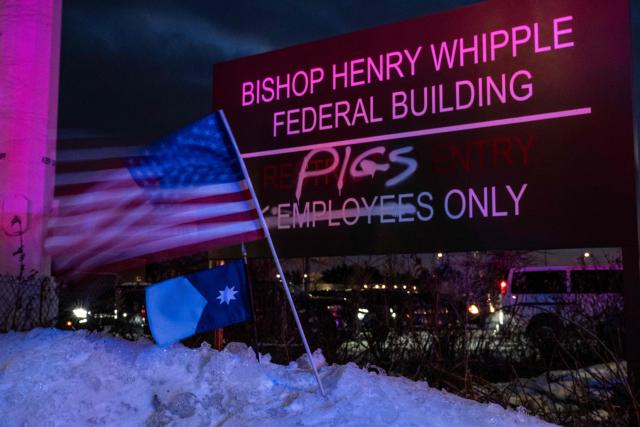 A US flag flutters in the wind near a defaced sign, spray-painted over to read "pigs" instead of "employees, outside the Bishop Henry Whipple Federal Building amid anti-US Immigration and Customs Enforcement (ICE) protests in Minneapolis, Minnesota on January 17, 2026. A US judge restricted federal agents on January 16 from interfering with peaceful protesters in Minnesota, after President Donald Trump said there was no immediate need to invoke the Insurrection Act over the demonstrations. (Photo by ROBERTO SCHMIDT / AFP)