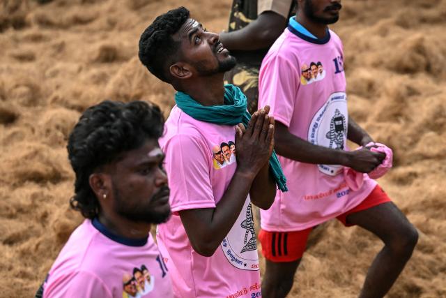 Bull wrestler Saravanan B (C) prays as he enters in the fighting arena during an annual bull-taming 'Jallikattu' festival in Palamedu village on the outskirts of Madurai on January 16, 2026. (Photo by R. Satish BABU / AFP) / To go with 'India-Bullfighting-Animal' , REPORTAGE