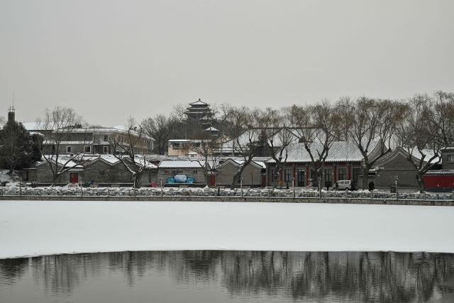 This photo shows a general view of the partially frozen Beihai Lake amid snowfall in Beijing on January 18, 2026. (Photo by ADEK BERRY / AFP)