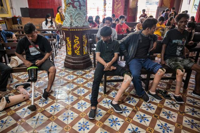 People wait to receive prosthetic legs, distributed for free to people with physical disabilities as part of a social service event by a Chinese foundation, at the Boen Bio Temple in Surabaya on January 18, 2026. (Photo by Juni KRISWANTO / AFP)