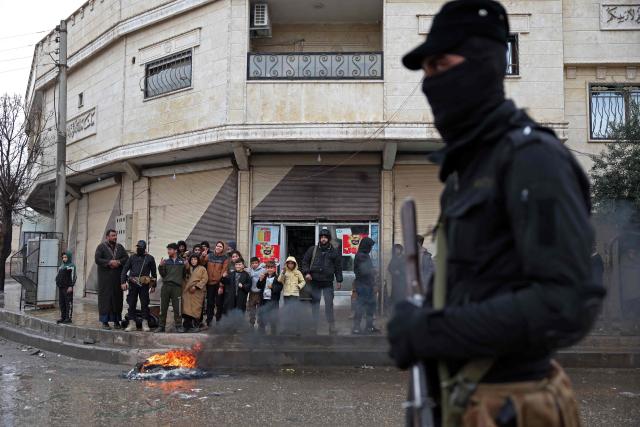 A Syrian government trooper patrols through a street as residents watch in Tabqa, in Raqa province, on the southwestern banks of the Euphrates on January 18, 2026. Kurdish-led forces withdrew on January 18 from Syria's largest oil field, a conflict monitor said, as government troops extended their grip over swathes of territory in the country's north and east. Government troops drove Kurdish forces from two Aleppo neighbourhoods following clashes last week, and on January 17 announced they had captured an area east of the city, as well as Tabqa. (Photo by OMAR HAJ KADOUR / AFP)