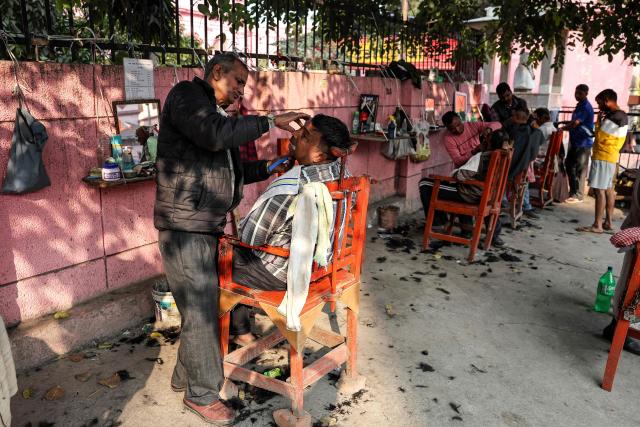 Men get a shave from roadside barbers in Varanasi on January 18, 2026. (Photo by Niharika KULKARNI / AFP)