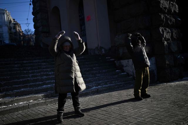 Practioners of the Falun Gong religious movement, also known as Falun Dafa, meditate on a street in Kyiv on January 18, 2026, amid the Russian invasion of Ukraine. (Photo by Sergei GAPON / AFP)