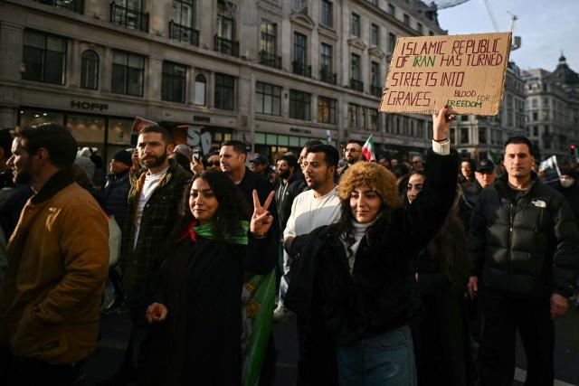 Protesters hold placards as they take part in a march to Downing Street against Iran's crackdown on protesters, in London on January 18, 2026. (Photo by JUSTIN TALLIS / AFP)