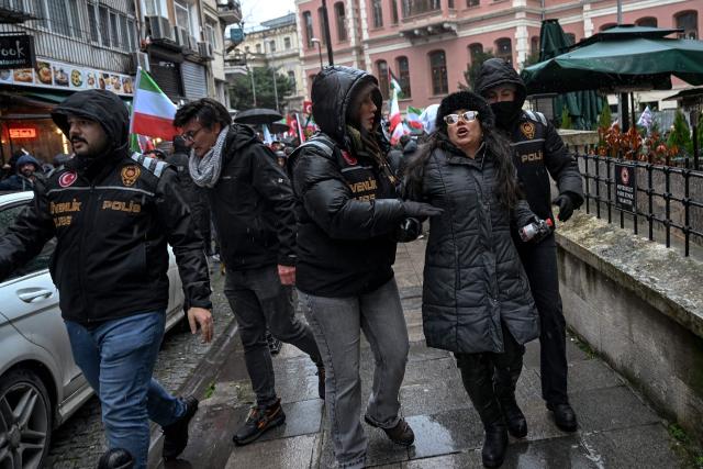 Turkish police datains a anti-regime protesters as she shout slogans against the Iranian regime during a pro-Iranian regime demonstration in front of the Iranian consulate in Istanbul, on January 18, 2026. Iranian authorities have said they are considering "gradually" restoring internet access after imposing an unprecedented communications shutdown 10 days ago, which rights groups say masked a violent protest crackdown that killed thousands. Demonstrations sparked in late December by anger over economic hardship exploded into protests widely seen as the biggest challenge to the Iranian leadership in years. (Photo by Ozan KOSE / AFP)