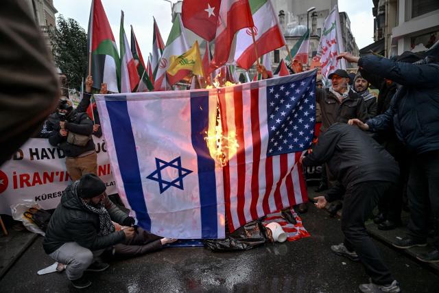 Protesters set afire a US Israel national flags as they shout slogans during a pro-Iranian regime demonstration in front of the Iranian consulate in Istanbul, on January 18, 2026. Iranian authorities have said they are considering "gradually" restoring internet access after imposing an unprecedented communications shutdown 10 days ago, which rights groups say masked a violent protest crackdown that killed thousands. Demonstrations sparked in late December by anger over economic hardship exploded into protests widely seen as the biggest challenge to the Iranian leadership in years. (Photo by Ozan KOSE / AFP)
