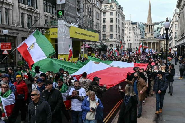 Protesters hold placards and Iran pre-1979 Revolution flags as they take part in a march to Downing Street against Iran's crackdown on protesters, in London on January 18, 2026. (Photo by JUSTIN TALLIS / AFP)
