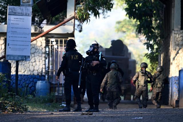 Riots police stand guard during a riot at the Renovacion I maximum-security prison in Escuintla, Guatemala, on January 18, 2026. Gang groups held more than 40 guards in several prisons in Guatemala on January 17 as they rioted in protest over the transfer of their leaders to a maximum-security facility, authorities said. (Photo by JOHAN ORDONEZ / AFP)