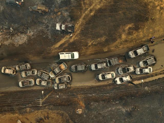 Aerial view of the remains of burned vehicles after a wildfire in Concepcion, Chile, on January 18, 2026. Chilean President Gabriel Boric declared a state of emergency on January 18 for two southern regions where raging wildfires have forced about 20,000 people to evacuate their homes. (Photo by Raul BRAVO / AFP)