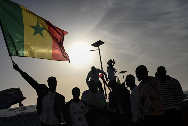 A Senegal football supporter waves a Senegalese flag at the Place du Souvenir Africain in Dakar on January 18, 2026 as supporters gather at a fan zone to watch the Africa Cup of Nations (CAN) final football match between Senegal and Morocco played in Rabat, Morocco. (Photo by Nicolas REMENE / AFP)