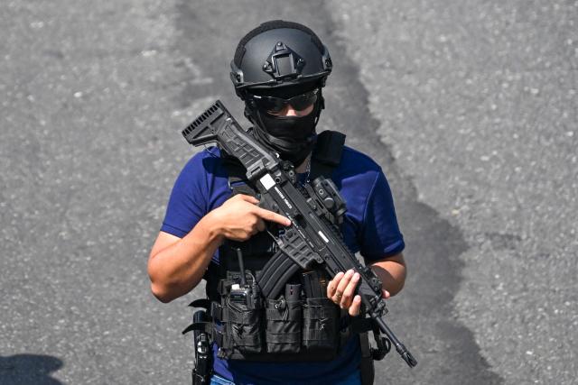 EDITORS NOTE: Graphic content / A police officer stands guard at the crime scene where a police officer was killed by alleged gang members in Guatemala City on January 18, 2025. Guatemala's interior minister accused gangs of killing seven police on Sunday in retaliation for the government's refusal to transfer gang leaders to a lower-security prison. (Photo by JOHAN ORDONEZ / AFP)