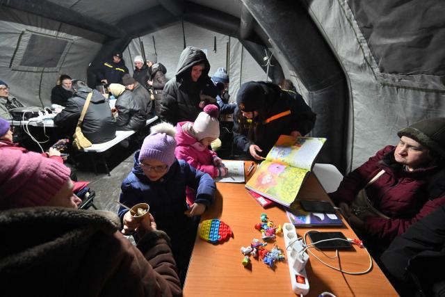 People sit in a tent, one of "Points of Invincibility", organized for residents to warm themselves and charge their electronic devices during blackout and heavy frost in Kyiv on January 18, 2026, amid Russian invasion in Ukraine. Russian attacks have left Ukraine's energy grid teetering on the brink of collapse and have disrupted power and water supplies to millions over recent weeks. (Photo by Sergei SUPINSKY / AFP)