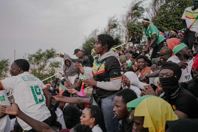 Senegalese football supporters react at the African Renaissance Monument in Dakar on January 18, 2026 as supporters gather at a fan zone to watch the Africa Cup of Nations (CAN) final football match between Senegal and Morocco played in Rabat, Morocco. (Photo by Carmen Abd Ali / AFP)