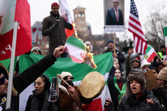 A man burns an Iranian flag while people sing and shout during a rally in support of the Iranian people in New York, on January 18, 2026. Protests in Iran have subsided after a crackdown that has killed thousands, monitors said on January 16, a week after the start of the largest demonstrations in years challenging the country's theocratic system. (Photo by CHARLY TRIBALLEAU / AFP)