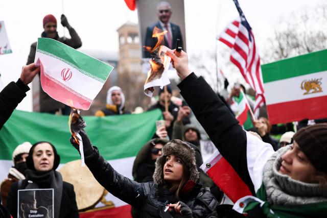 Demonstrators burn an Iranian flag and a photo of Iranian Supreme Leader, Ali Khamenei, as people sing and shout during a rally in support of the Iranian people in New York, on January 18, 2026. Protests in Iran have subsided after a crackdown that has killed thousands, monitors said on January 16, a week after the start of the largest demonstrations in years challenging the country's theocratic system. (Photo by CHARLY TRIBALLEAU / AFP)