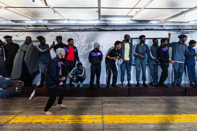 Migrants react as they play football onboard the rescue ship 'Ocean Viking' operated by the NGO SOS Mediterranee, as it sails in the Mediterranean Sea toward the designated port of disembarkation in Palermo, southern Italy, on January 18, 2026. (Photo by Sameer Al-DOUMY / AFP)