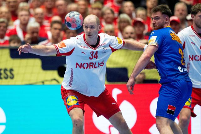 Denmark's pivot #34 Simon Hald Jensen (L) and Romania's right back #25 Ionut Adrian Stanescu vie for the ball during the men's EHF Euro 2026 preliminary round group B handball match Romania vs Denmark in Herning, Denmark, on January 18, 2026. (Photo by Bo Amstrup / Ritzau Scanpix / AFP) / Denmark OUT