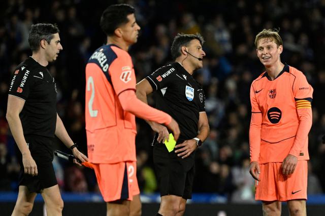 FC Porto's Dutch forward #26 Luuk De Jong (R) is presented a yellow card by Spanish referee Jesus Gil during the Spanish league football match between Real Sociedad and FC Barcelona at Anoeta Stadium in San Sebastian on January 18, 2026. (Photo by ANDER GILLENEA / AFP)