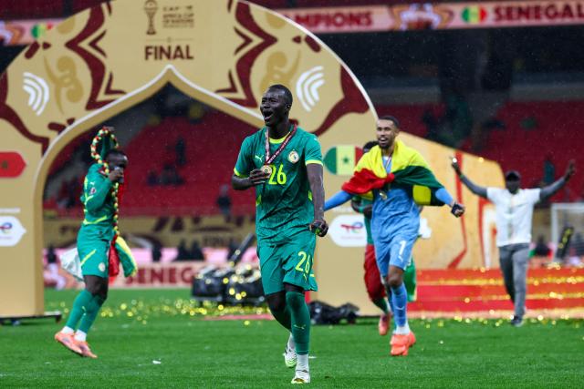 Senegal's midfielder #26 Pape Gueye (C) and his teammates celebrate their victory at the end of the Africa Cup of Nations (CAN) final football match against Morocco at the Prince Moulay Abdellah Stadium in Rabat on January 18, 2026. (Photo by FRANCK FIFE / AFP)
