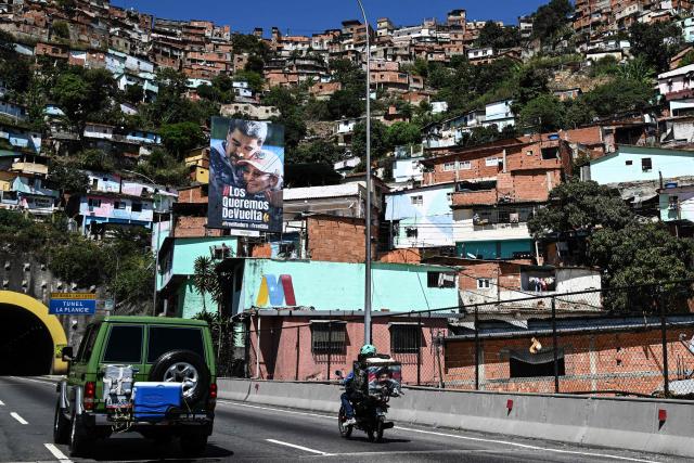 A billboard featuring an image of ousted Venezuelan President Nicolas Maduro and his wife Cilia Flores reads “We want you back,” in La Guaira, Venezuela on January 18, 2026. (Photo by Ronaldo SCHEMIDT / AFP)