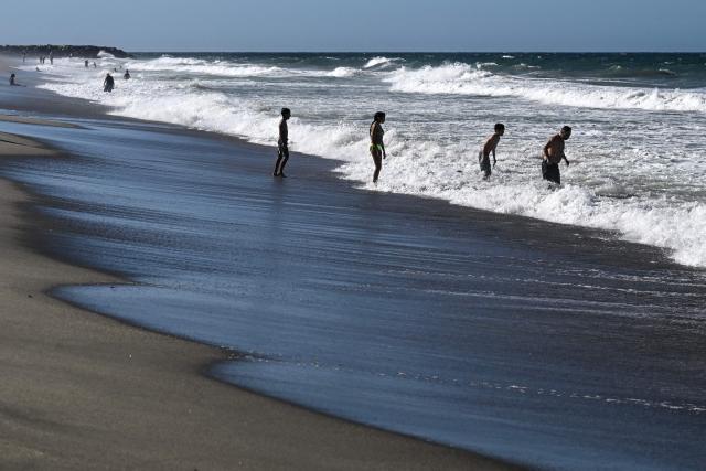 People hang out at the beach in La Guaira, Venezuela on January 18, 2026. (Photo by Ronaldo SCHEMIDT / AFP)